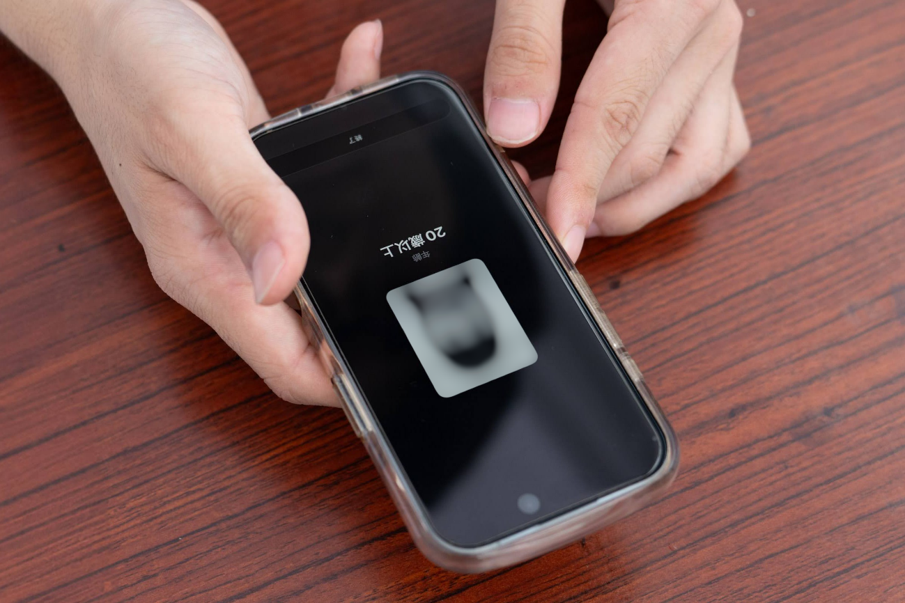 スタッフが持つスマートフォンに、読み取り結果として「20歳以上」の表示と、ぼかし処理された顔写真が映っている様子。