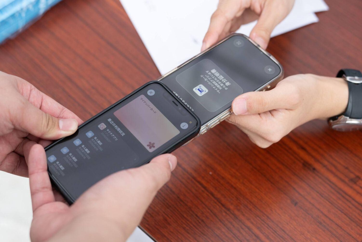 スタッフが持つスマートフォンに、読み取り結果として「20歳以上」の表示と、ぼかし処理された顔写真が映っている様子。