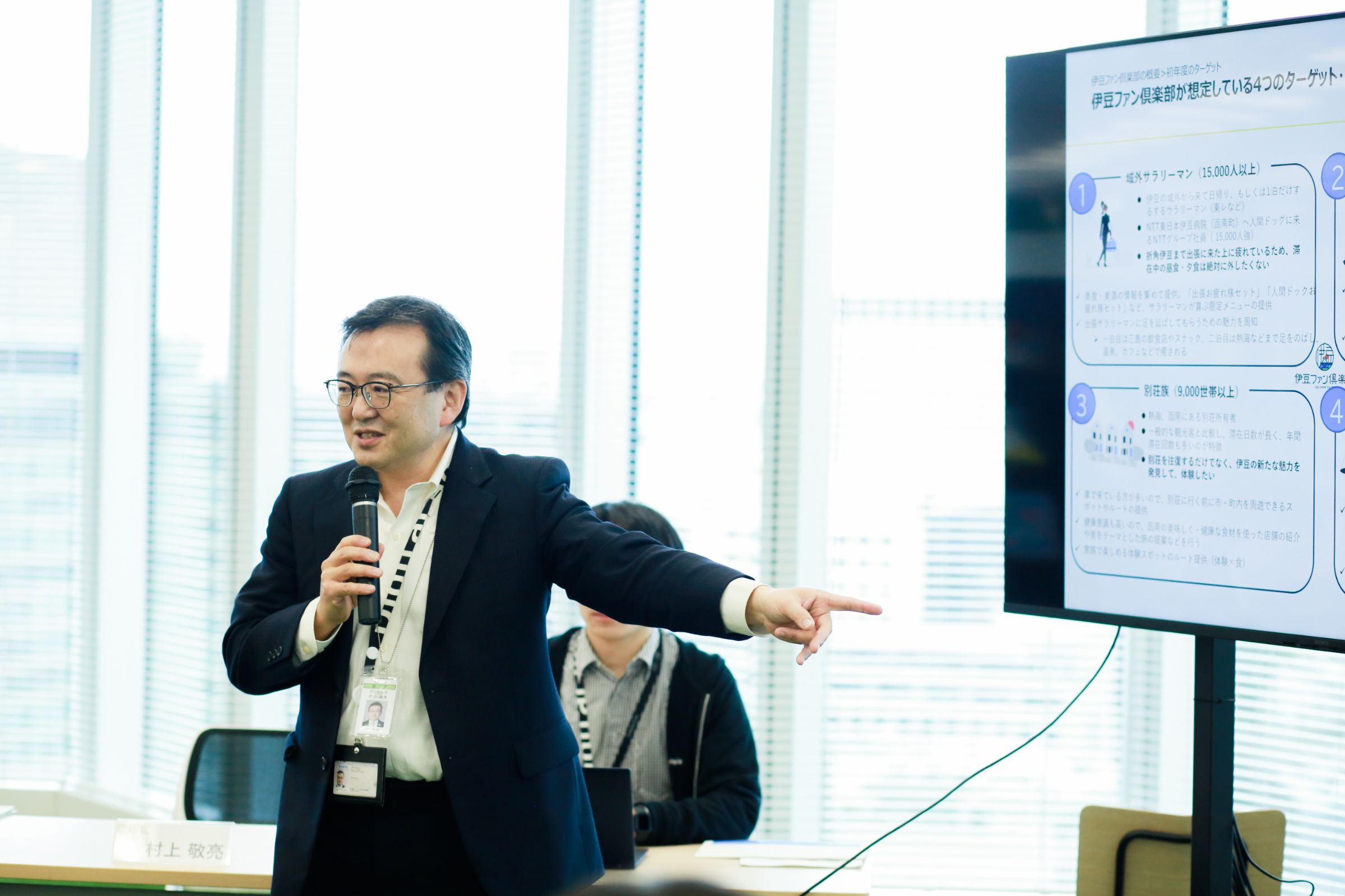 「人口が減る局面ではデジタルとデータが必要です」と語るデジタル庁 統括官村上敬亮がモニターを指さして話している様子