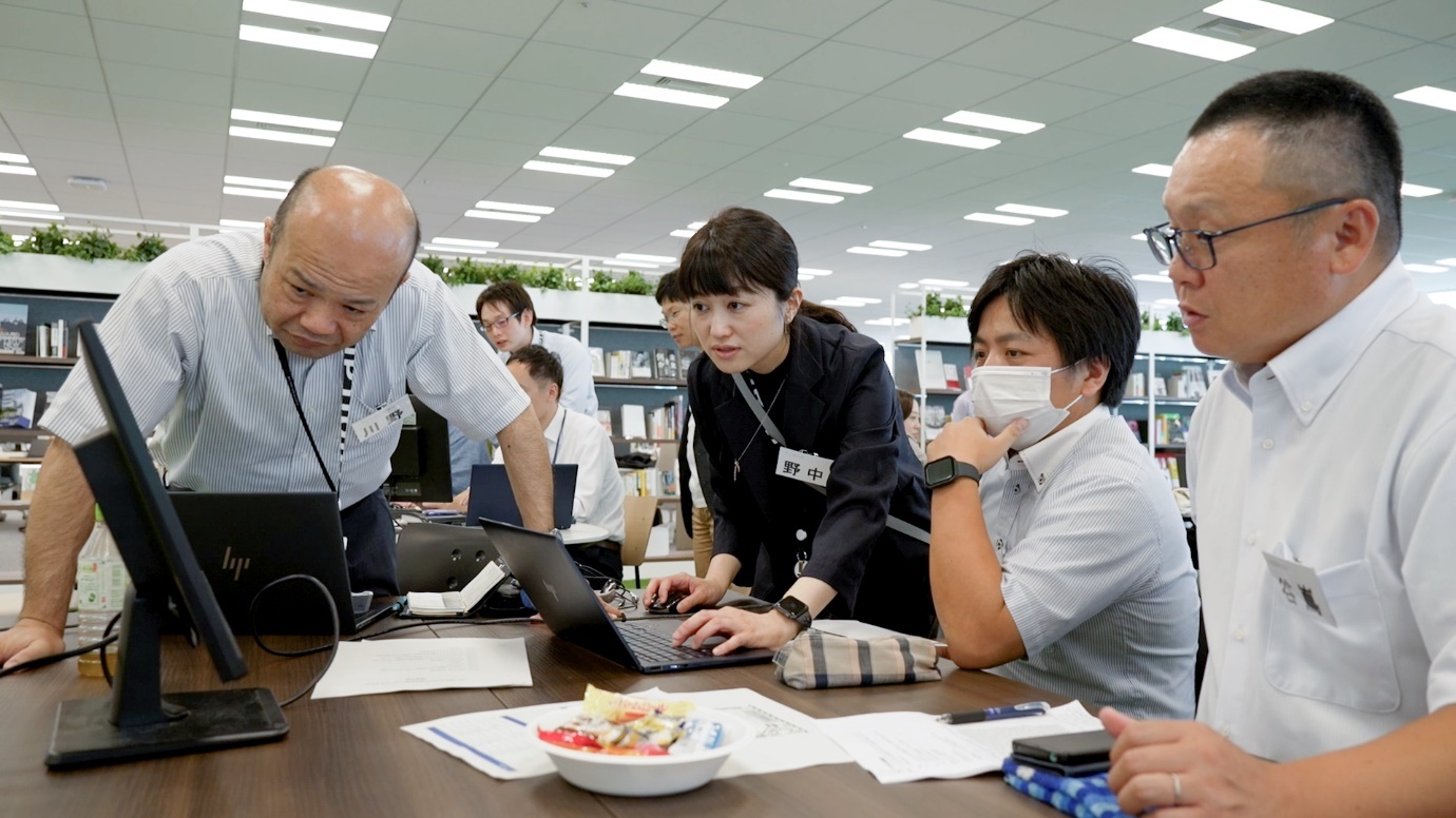 ワークショップの様子を写した写真。パソコンにつないだモニターを参加者が覗いている。