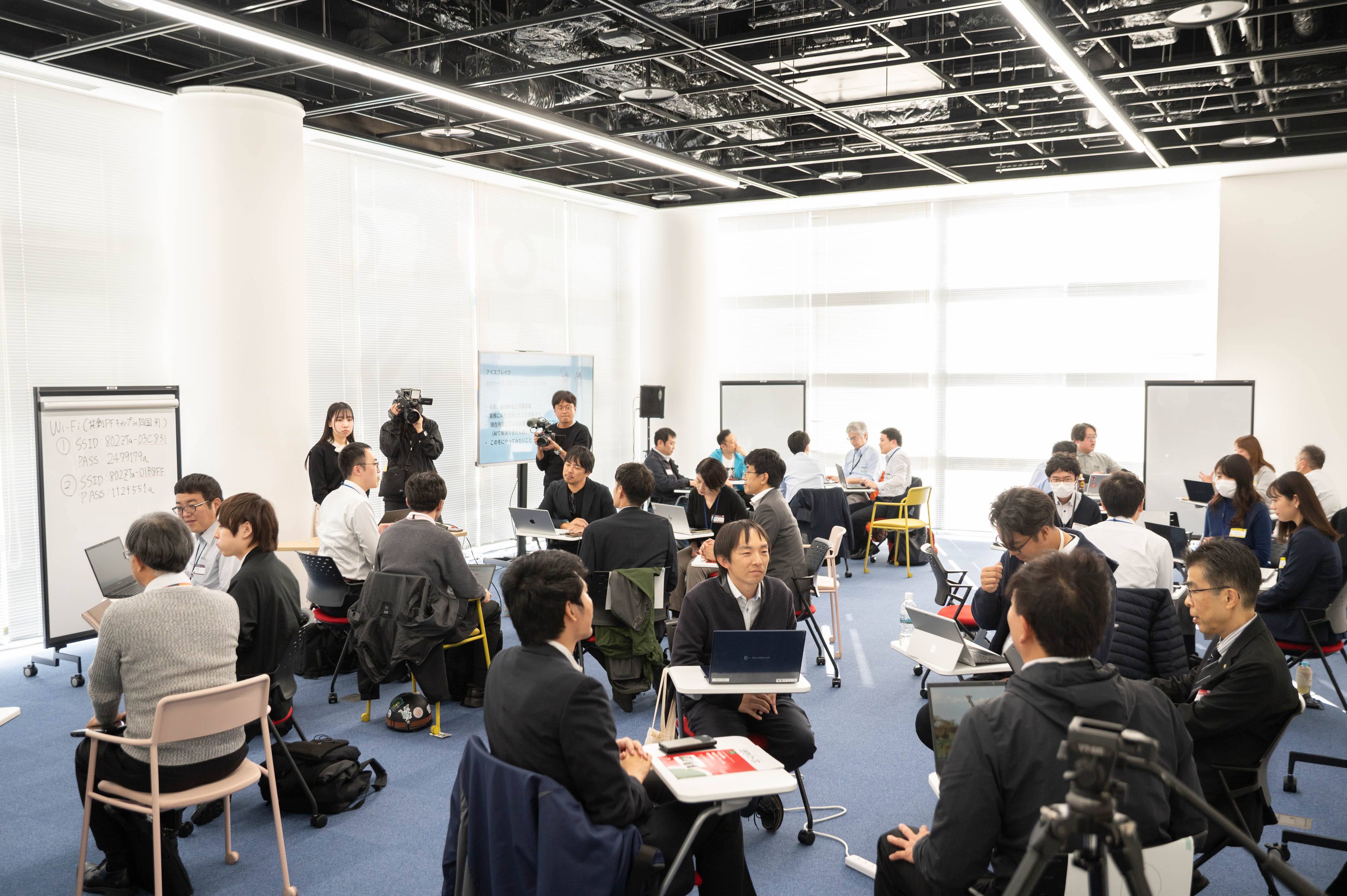 共創PFキャンプの会場の様子をうつしている。参加者は5~6人一組で車座で着席し、話し合いをしている。