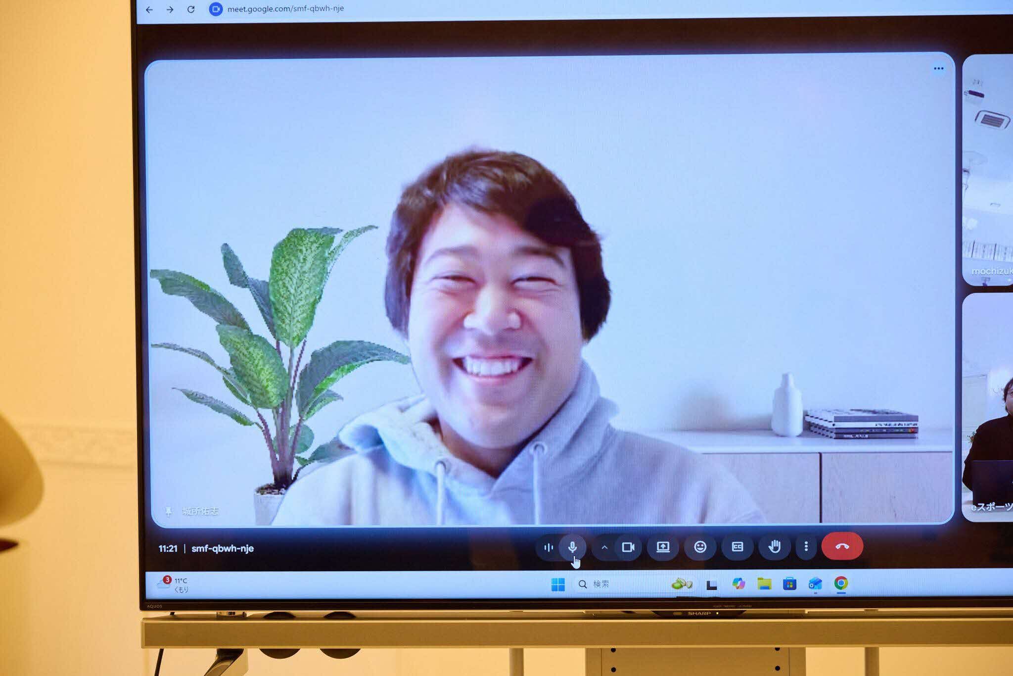 モニター画面に映し出された一般社団法人asolabマネージャーの城所佑志さんとのビデオ通話画面。背景には観葉植物と白い陶器の花瓶、本が置かれたロー棚が見える。