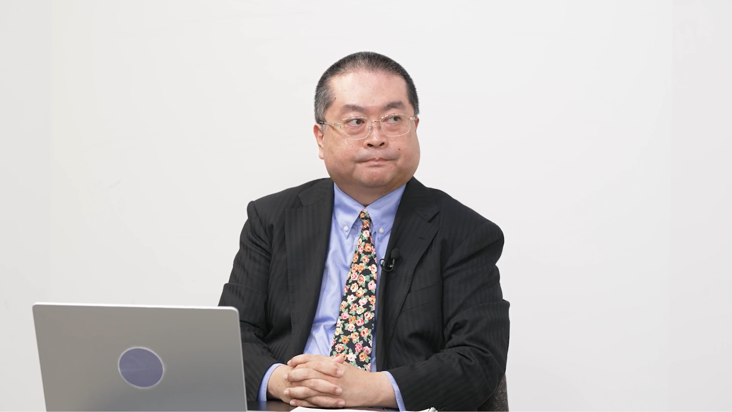 デジタル庁の山口真吾参事官。着席している様子を正面から撮影。手元には資料とノートパソコンが置かれている。