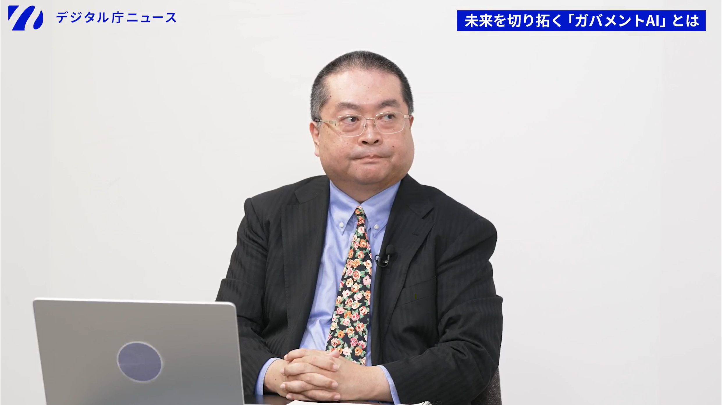 デジタル庁の山口真吾参事官。着席している様子を正面から撮影。手元には資料とノートパソコンが置かれている。