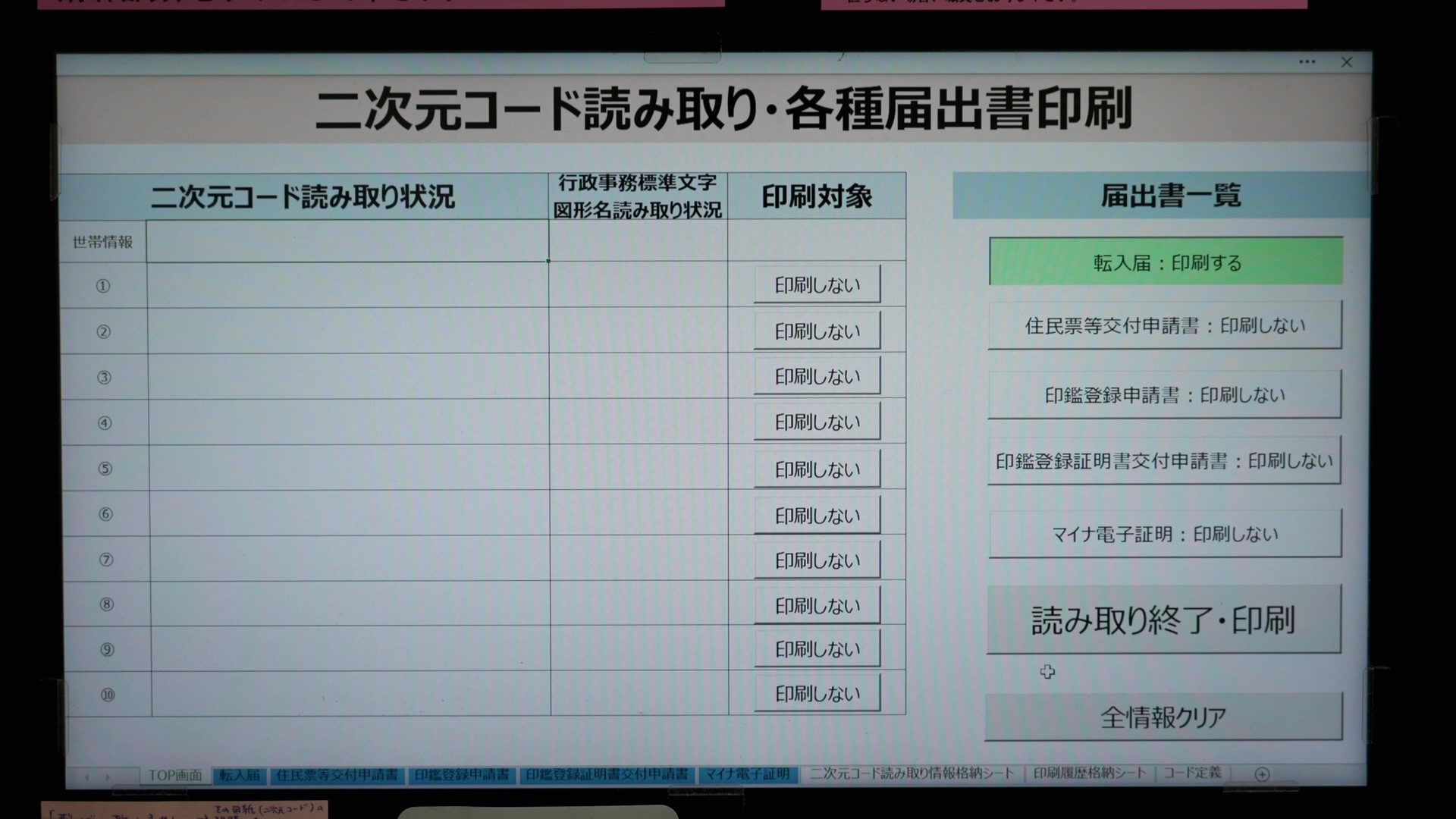 PCの業務用アプリケーション画面のスクリーンショット。タイトルは「二次元コード読み取り・各種届出書印刷」。左側テーブルには「二次元コード読み取り状況」「行政事務標準文字図形名読み取り状況」「印刷対象」の列があり、「印刷対象」の列には世帯情報と①〜⑩の行すべてに「印刷しない」ボタンが並ぶ。右側「届出書一覧」には「転入届：印刷する（緑で強調）」「住民票等交付申請書：印刷しない」「印鑑登録申請書：印刷しない」「印鑑登録証明書交付申請書：印刷しない」「マイナ電子証明：印刷しない」が表示され、下部に「読み取り終了・印刷」「全情報クリア」ボタンがある。画面下部にはタブ（TOP画面・転入届・住民票等交付申請書・印鑑登録申請書・印鑑登録証明書交付申請書・マイナ電子証明・二次元コード読み取り情報格納シート・印刷履歴格納シート・コード定義）が並んでいる。