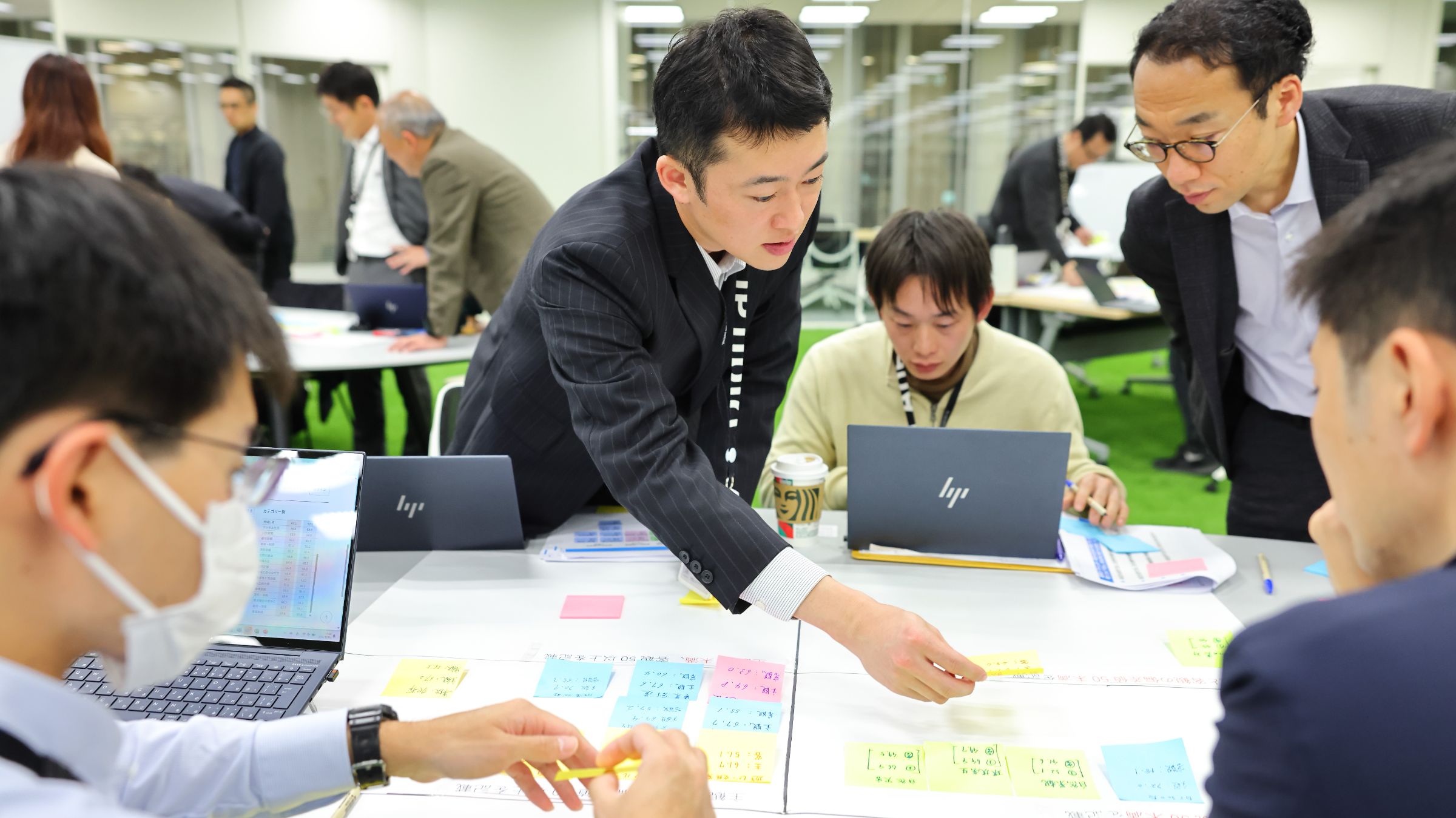 2024年12月に開催したワークショップの様子。男性5人が付箋を使ってワークショップをしている様子の写真
