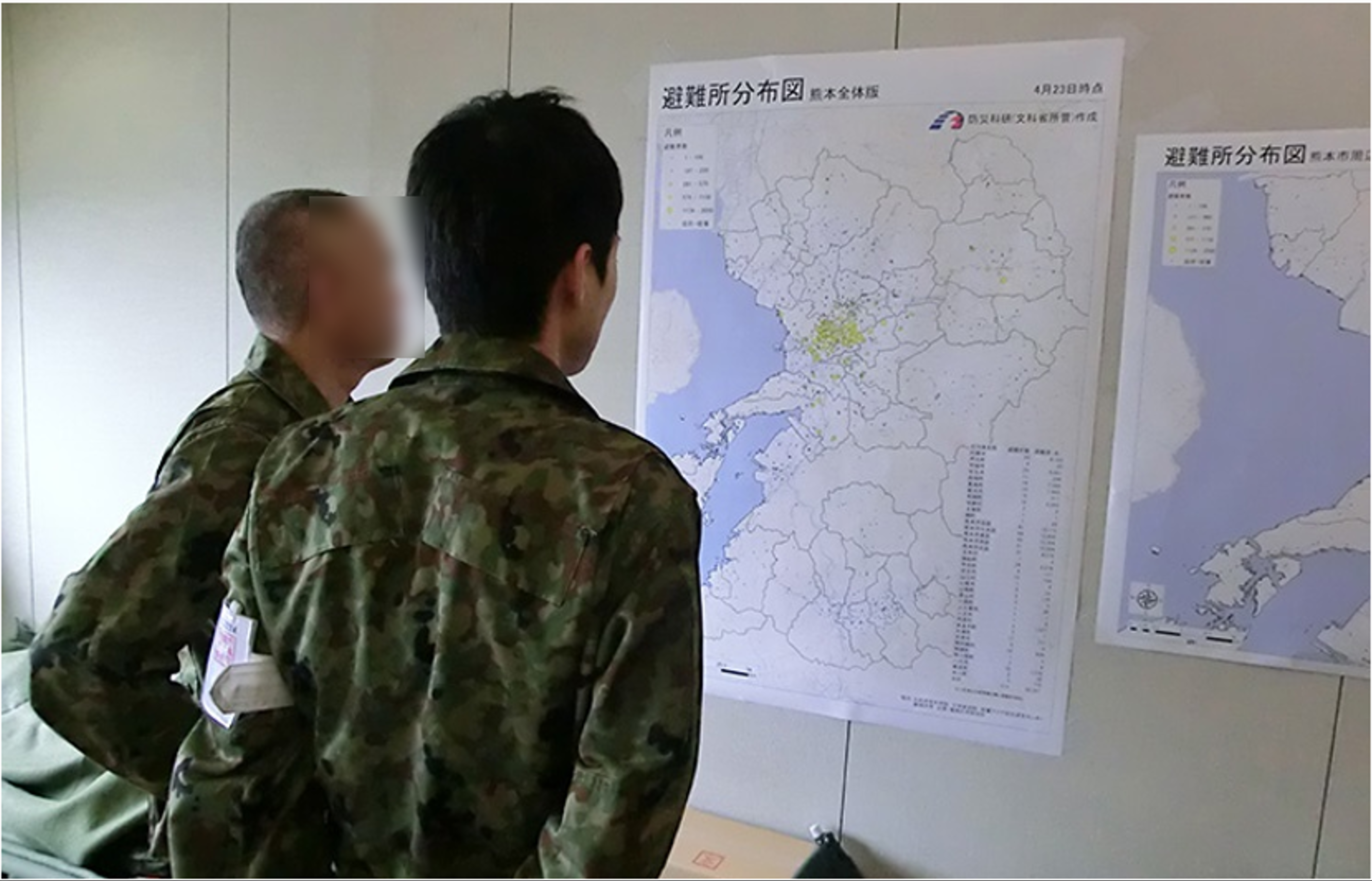 壁に貼られた「避難所分布図」を眺める、熊本県災害対策本部関係者を背後から撮影した写真(2016年)。